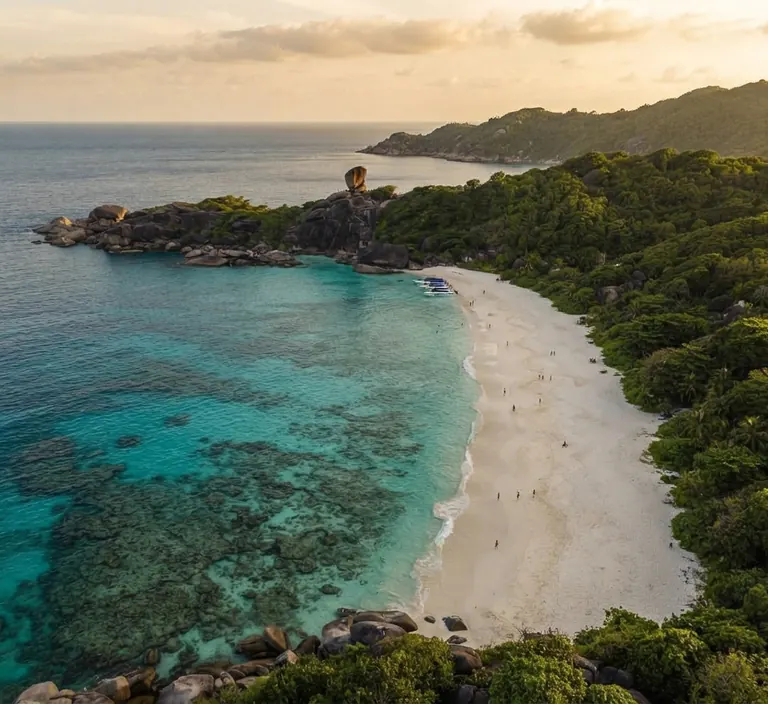 Aerial view of a long white beach curving beside a fringing reef