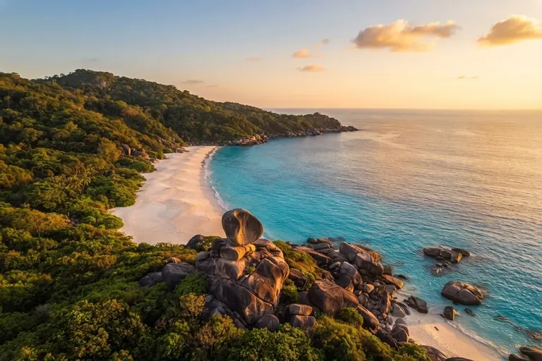 Sunset over a white beach and the Sail Rock viewpoint hill seen from above