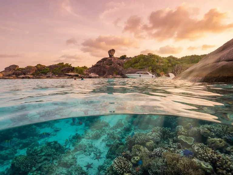 Split view at sunset of a coral reef below the waterline and Sail Rock above