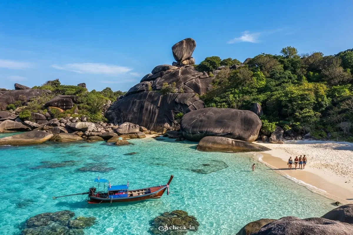 Longtail boat in turquoise water below Sail Rock with visitors on the beach