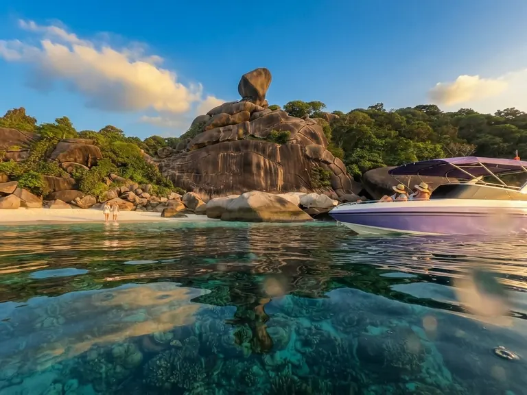 Speedboat moored beside Sail Rock on mirror-calm water