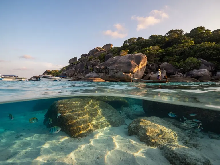 Split view of submerged granite boulders below a rocky islet