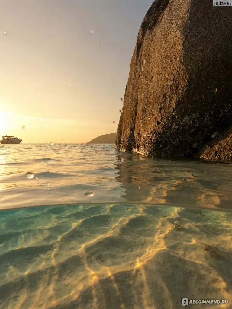 Sunlit shallow water beside a tall granite boulder